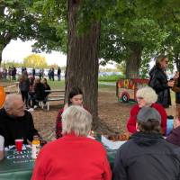 People sitting on a bench enjoying cider and donut